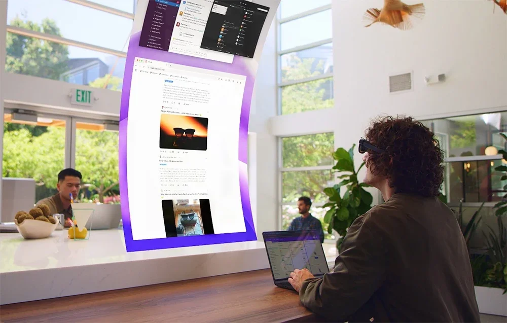 Cilvēks sēž gaišā istabā ar klēpjdatoru un izmanto XR brilles