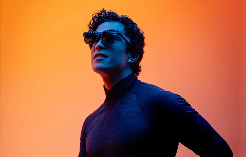 Vīrietis ar XR brillēm uz oranža fona