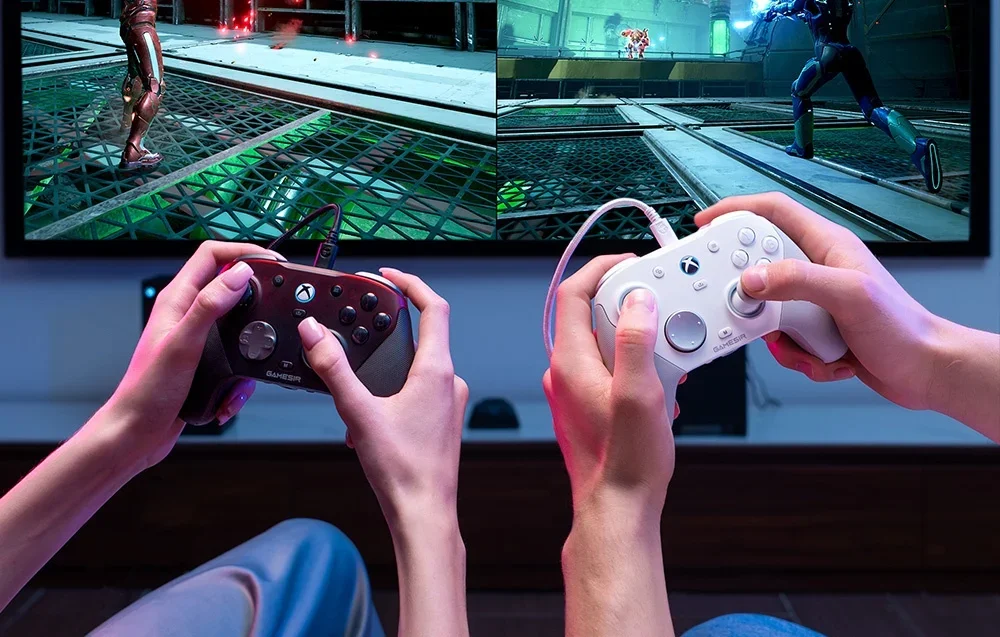Tuvplāns ar divu cilvēku rokām, kas tur GameSir kontrolierus, spēlējot pie televizora.