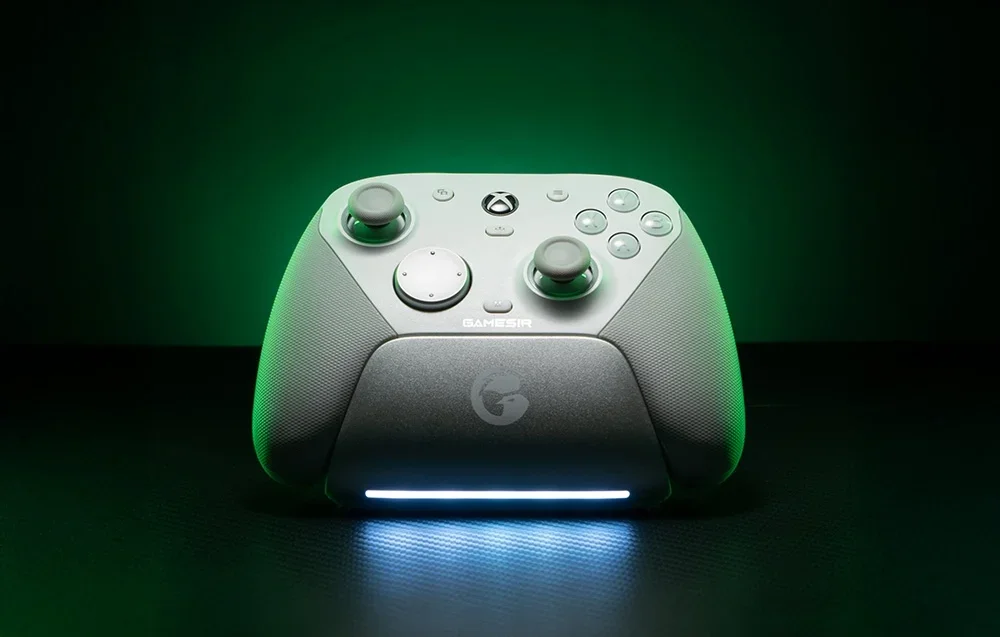 Balts GameSir kontrolieris dokstacijā ar LED apgaismojumu zaļas gaismas fonā.
