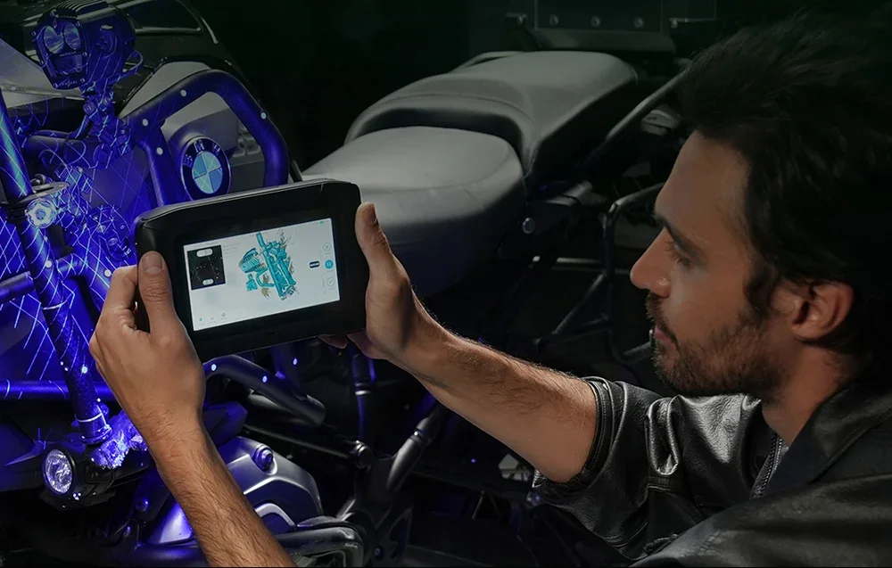 Rokas 3D scanner pavērsts pret BMW motocikla dzinēju