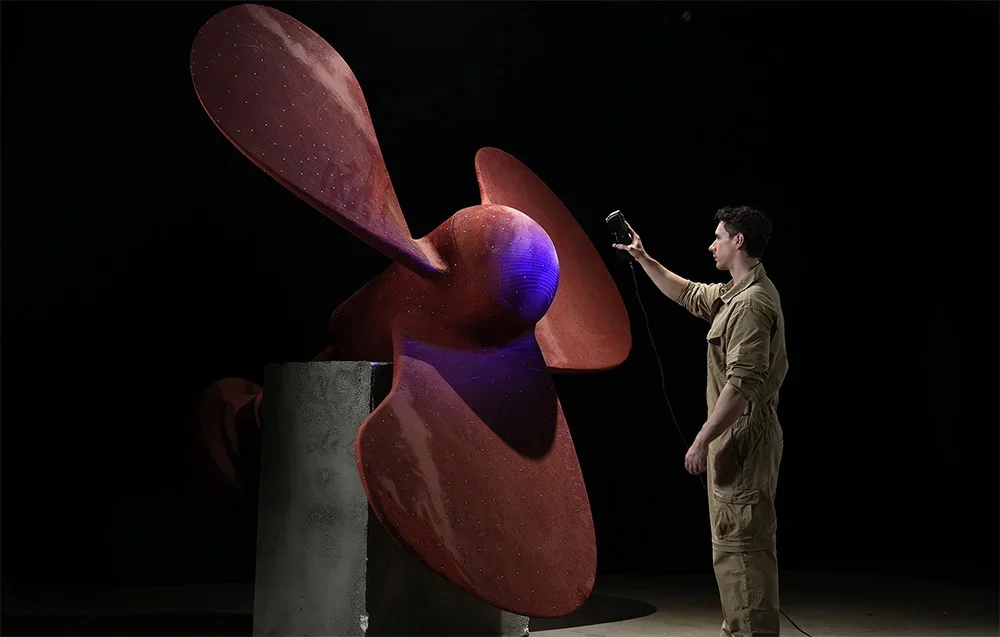 Tehniķis skenē lielu sarkanu kuģa dzenskrūvi ar 3D scanner